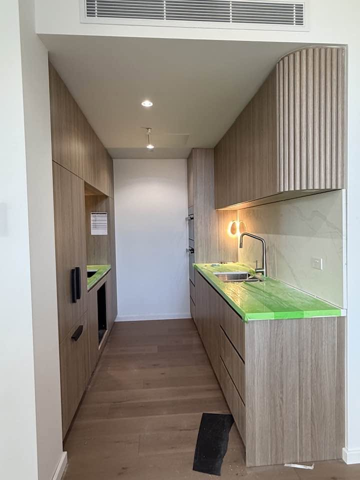 Narrow kitchen installation with light wood cabinetry